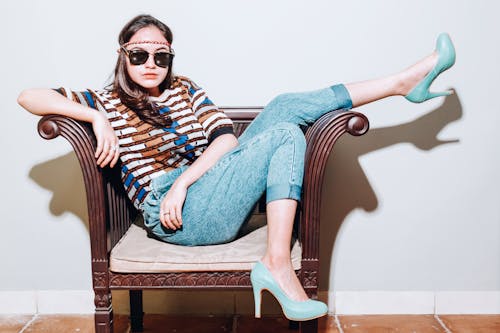 Woman in Blue Denim Jeans Sitting on Brown Wooden Armchair