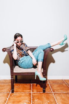 Fashionable woman in casual attire posing on a chair in Jakarta.
