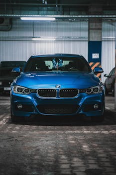 Front view of a stylish blue car parked in a well-lit garage.