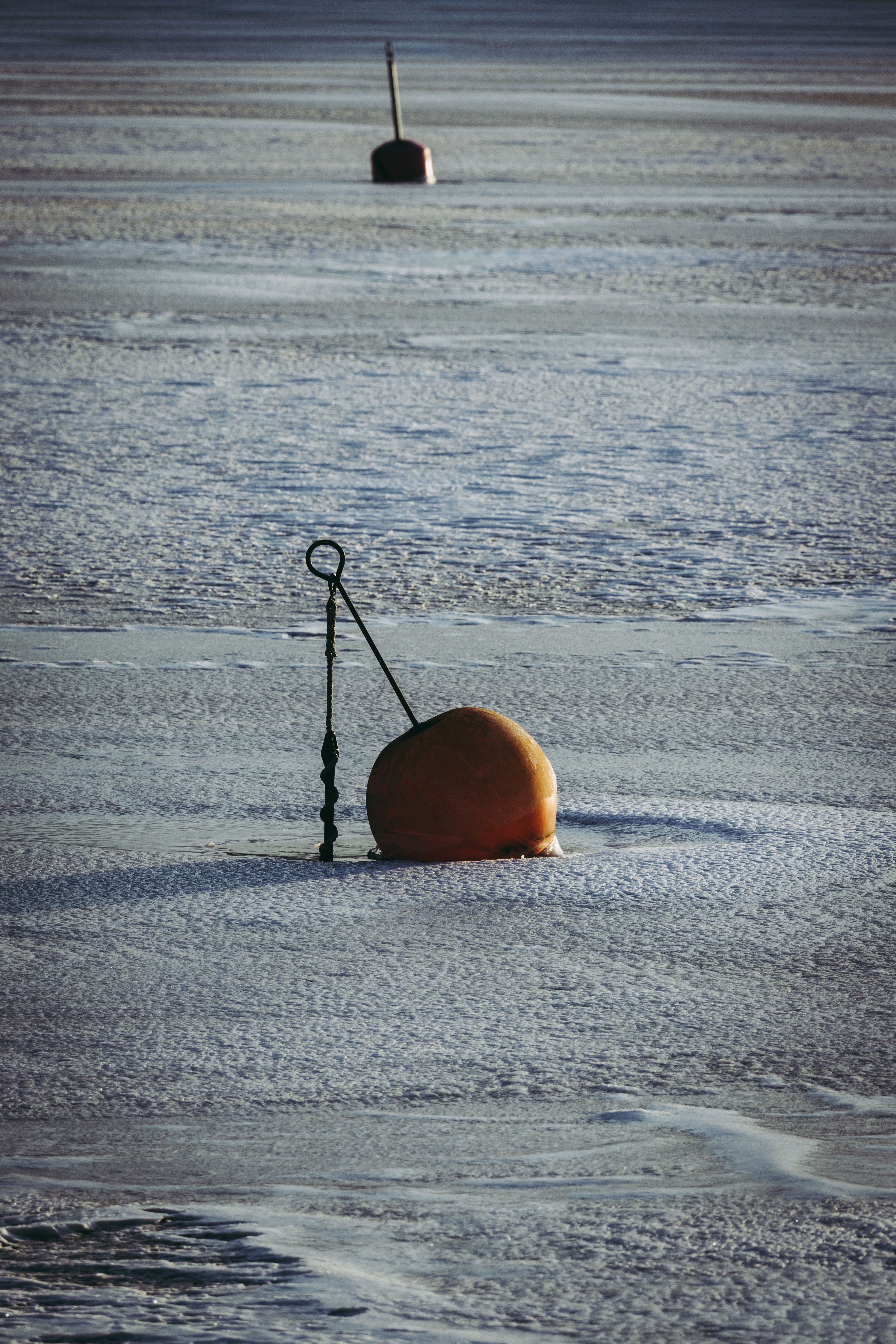 Two buoys on a serene frozen lake surface creating a tranquil winter scene.