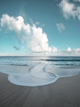 Calming ocean view with clouds and gentle waves on a Hawaiian beach.