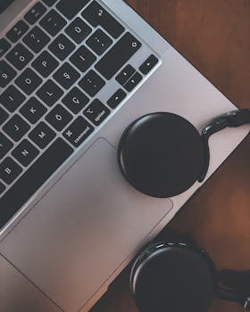 A minimalist close-up image of a laptop and headphones, showcasing modern technology essentials.