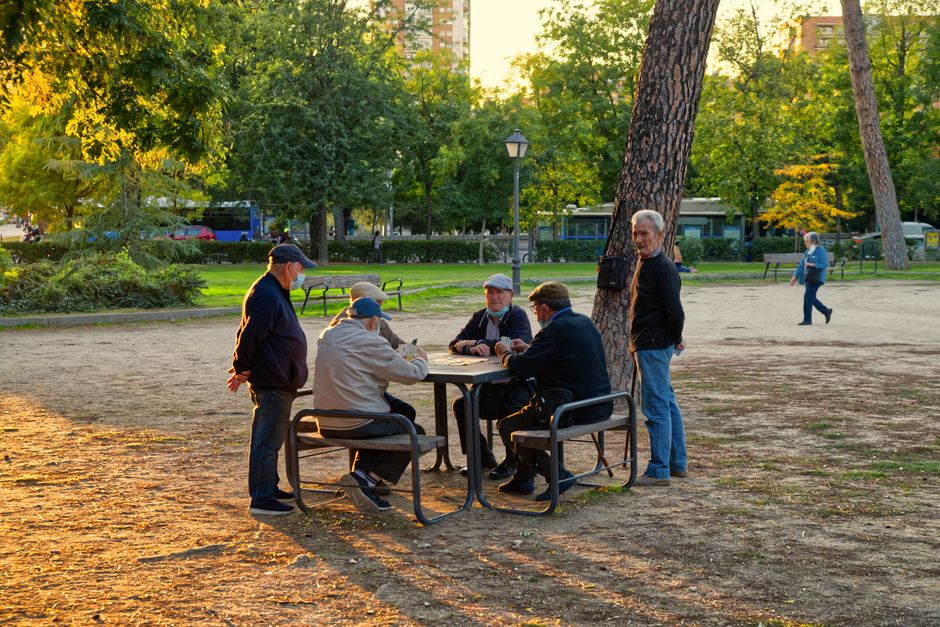 Un grupo de hombres mayores jugando a un juego en un soleado parque de Madrid, disfrutando de la recreación y la amistad.