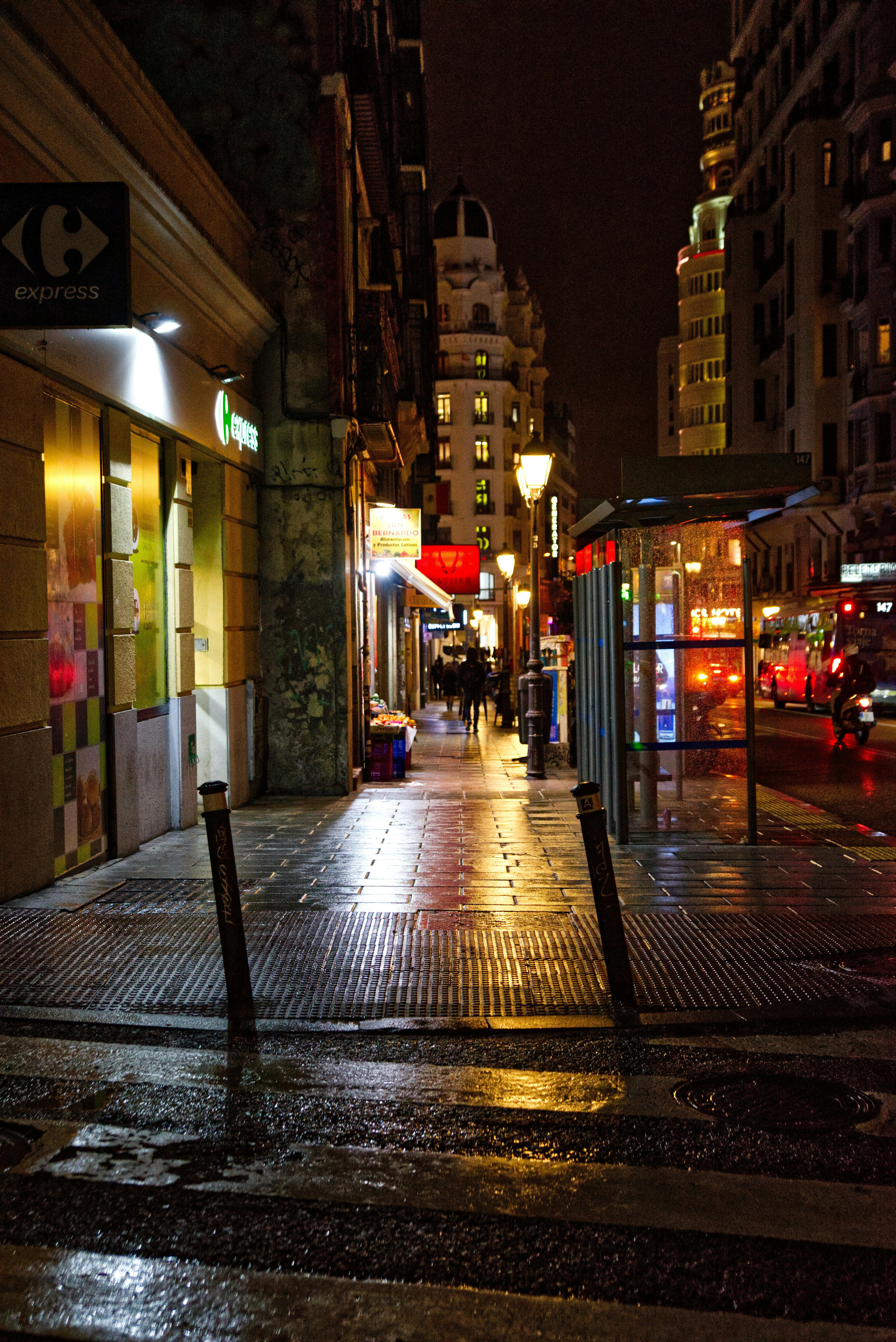 illuminated city street in rain by night