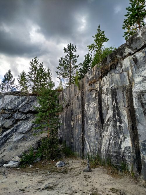 Free Explore the striking marble cliffs and lush green trees under a moody cloudy sky in Karelia, Russia. Stock Photo