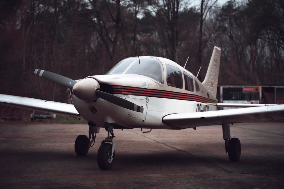 A detailed view of a single-engine small aircraft parked on a runway surrounded by trees.