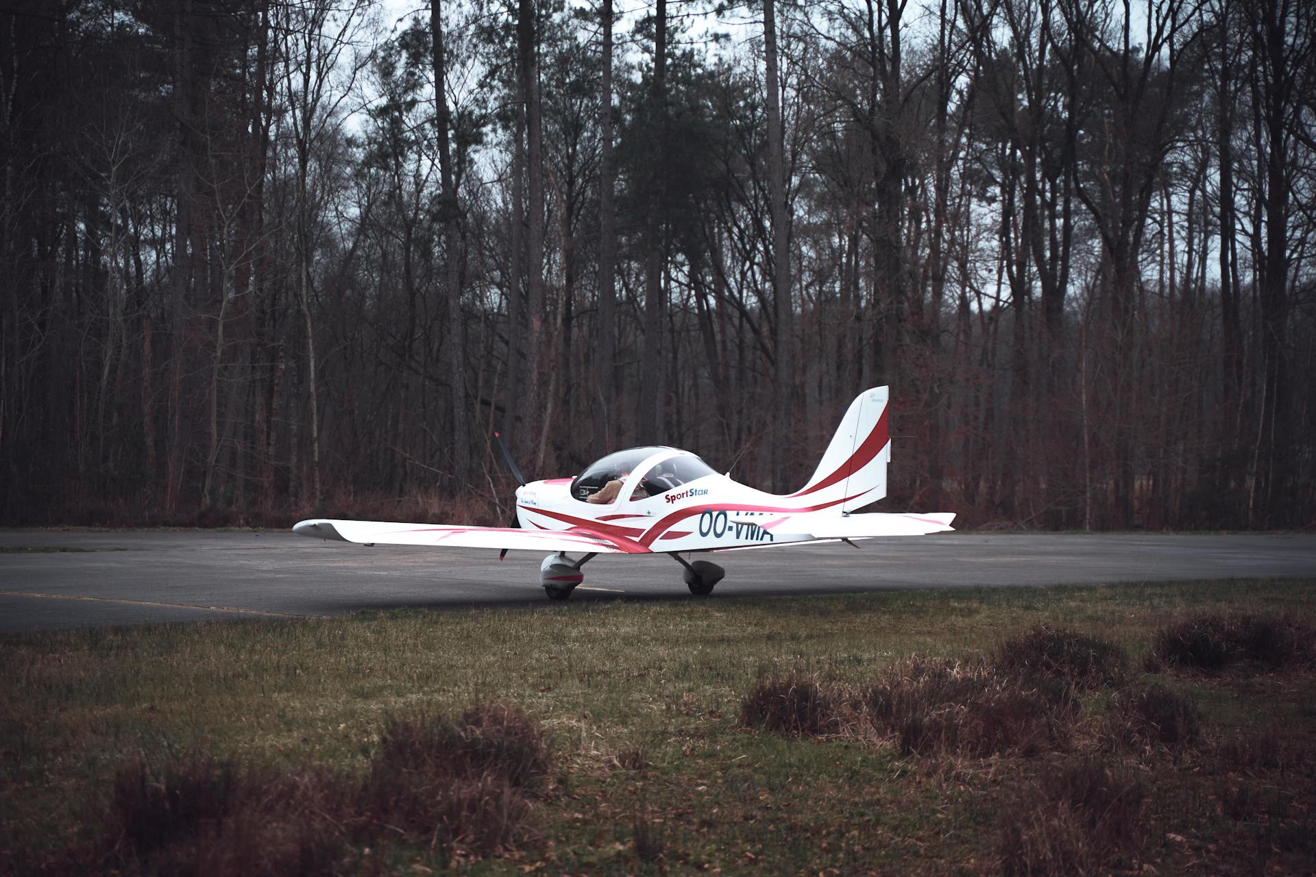 A private plane parked on a tarmac near a forest clearing, captured during winter.