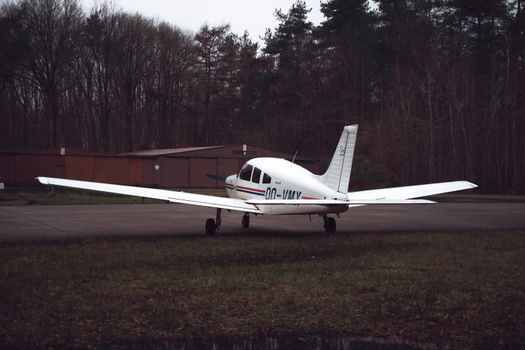 A small airplane parked on a runway surrounded by trees in a forested area.