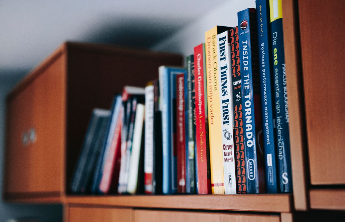 A variety of books neatly arranged on a wooden bookshelf.