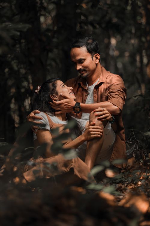 Free A couple sits lovingly together in a serene forest, capturing a moment of affection and connection. Stock Photo