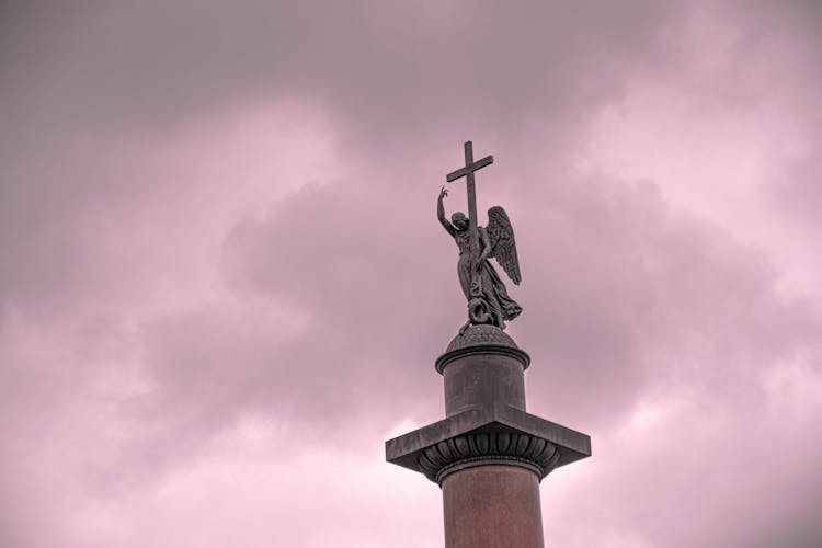 Angel With Cross Statue Against Pink Sky