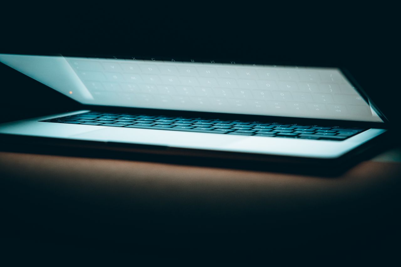 a close up of a partially open laptop on a wooden surface displayed in