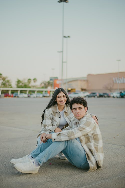 Free Man and Woman Sitting on Car Park Stock Photo