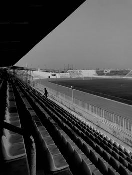 Black and white photo of empty soccer stadium bleachers capturing solitude.
