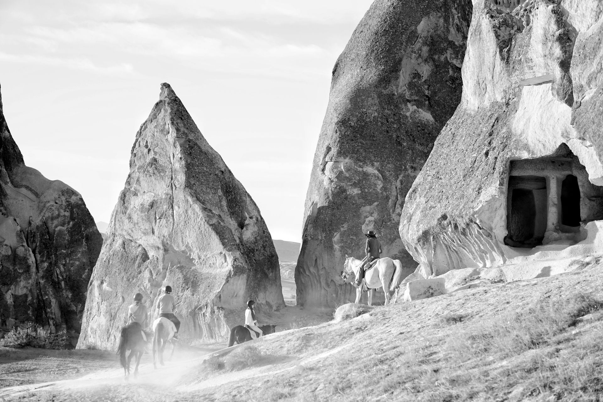 Horseback riders exploring rocky terrain in a captivating black and white setting.
