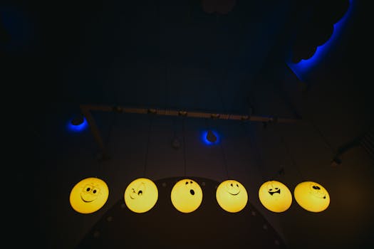 Close-up of illuminated emoji lanterns with varied expressions hanging indoors, creating a playful atmosphere.