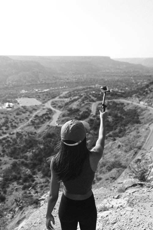 Free A woman holding a camera captures stunning views atop a Colorado mountain. Grayscale photograph. Stock Photo