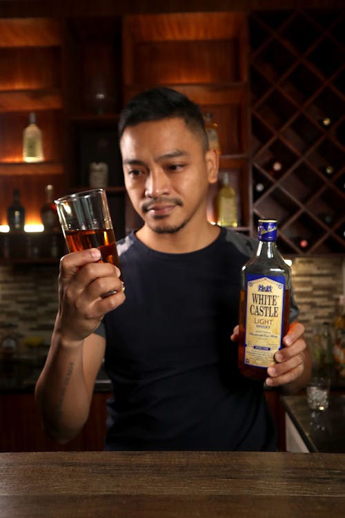 A Man Holding a Glass and Bottle of Whisky 