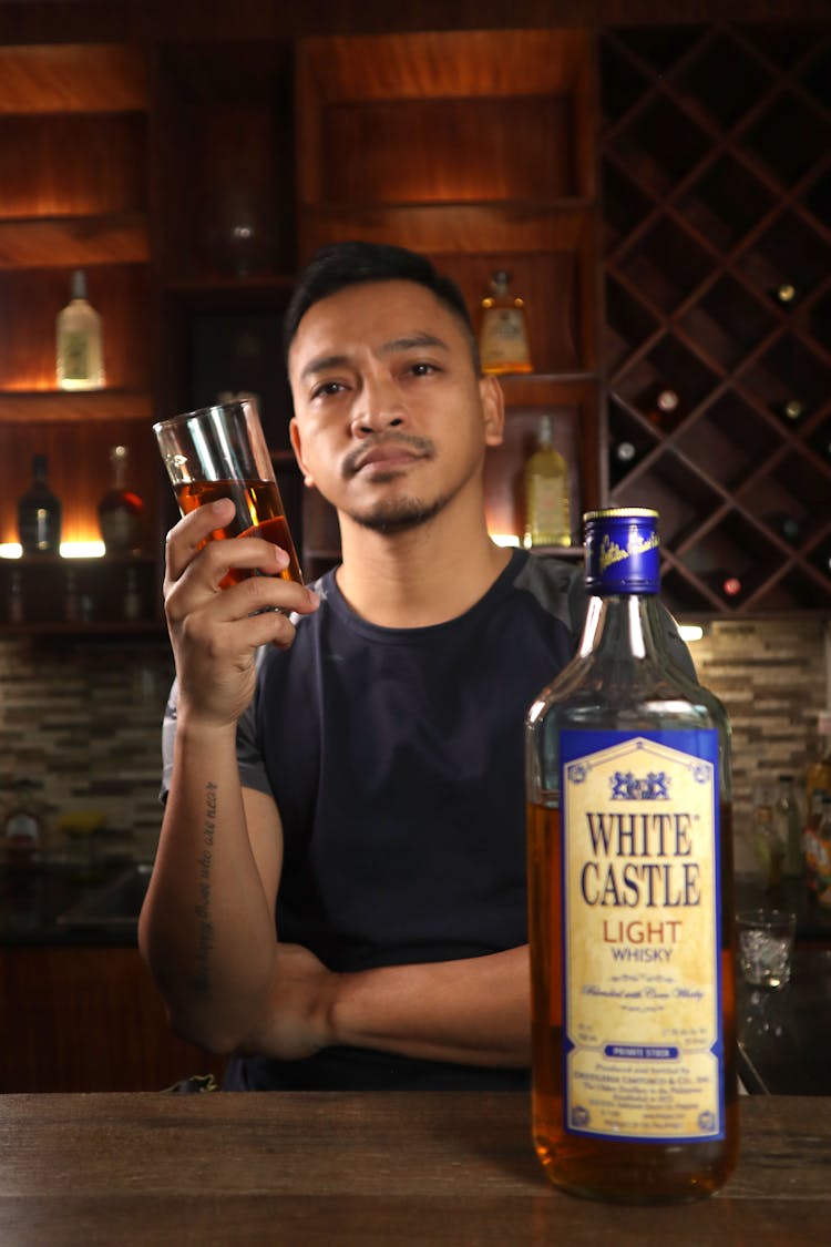 Man Holding A Glass Of Whisky At The Bar