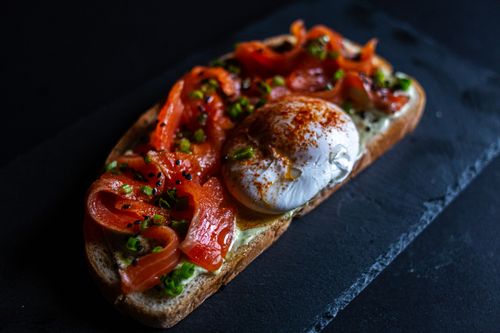 Free Delicious gourmet smoked salmon and poached egg sandwich with herbs, perfect for lunch. Stock Photo