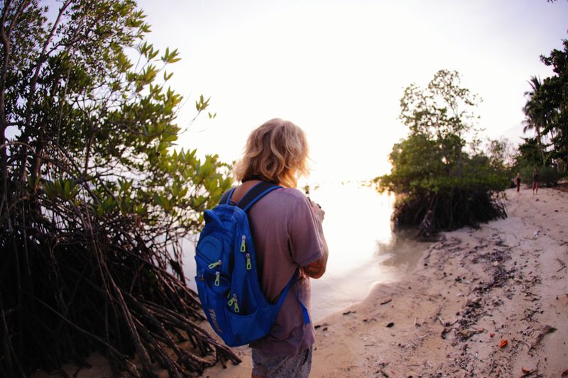 A solo backpacker explores a tropical beach at sunset