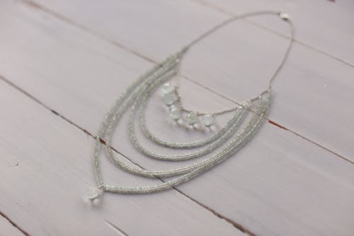 Silver Necklace on White Wooden Table