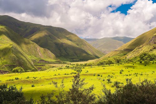 Green Grass Field and Mountain Under White Clouds