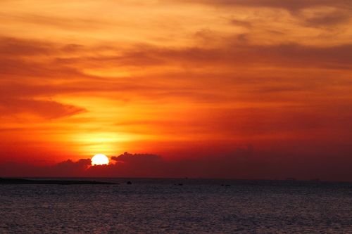 Free Capture of a vivid sunset over the ocean with dramatic clouds and warm colors. Stock Photo