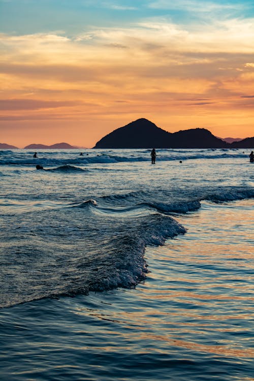 People Swimming on the Beach at Sunset