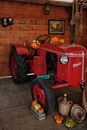 Red Tractor in Front of Brown Brick Wall