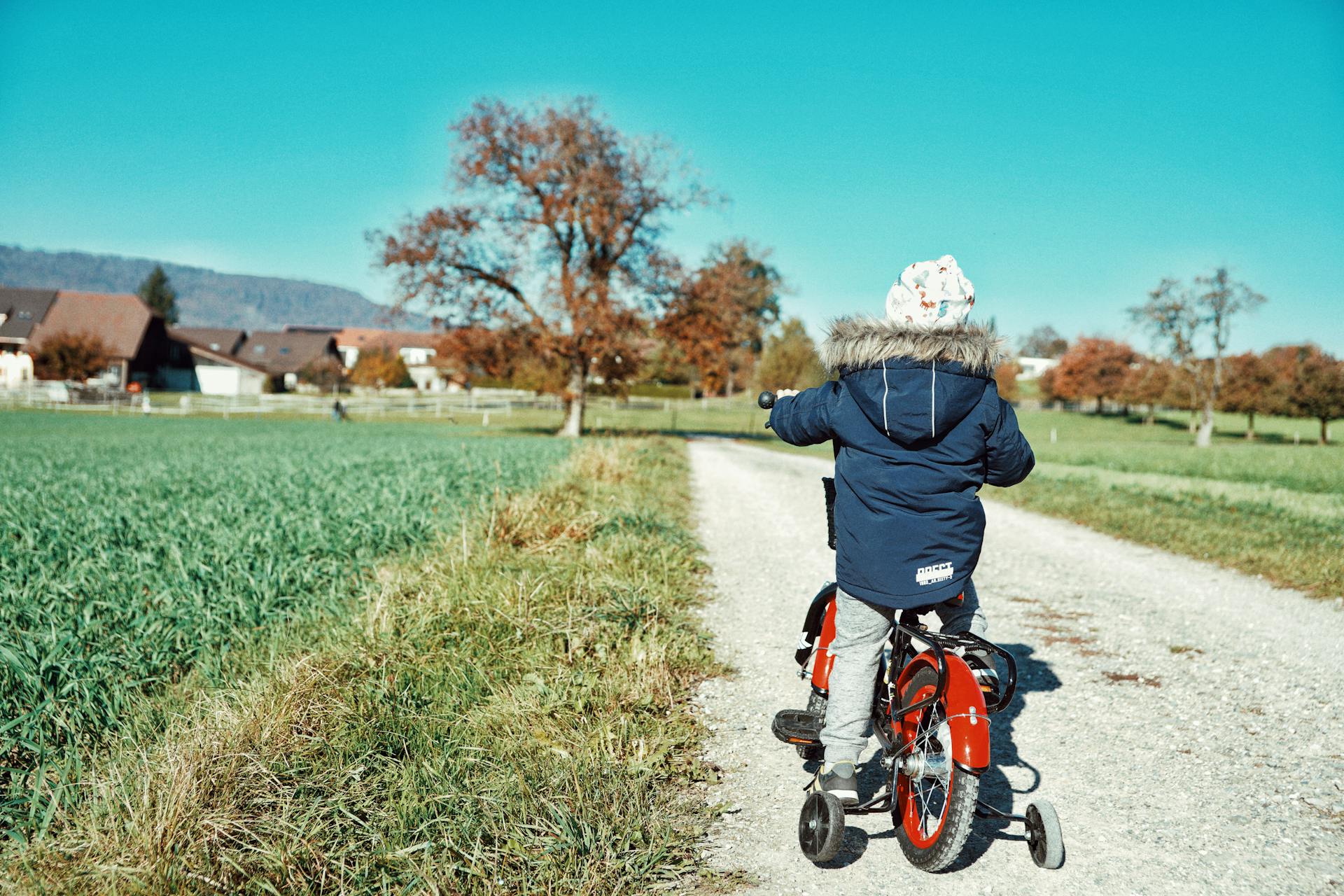 A Kid Biking on the Farm Road
