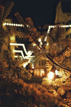 Twinkling Christmas lights illuminating a city street with festive decorations.