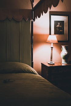Warm-toned bedroom featuring a vintage lamp, elegant vase, and classic interior design.