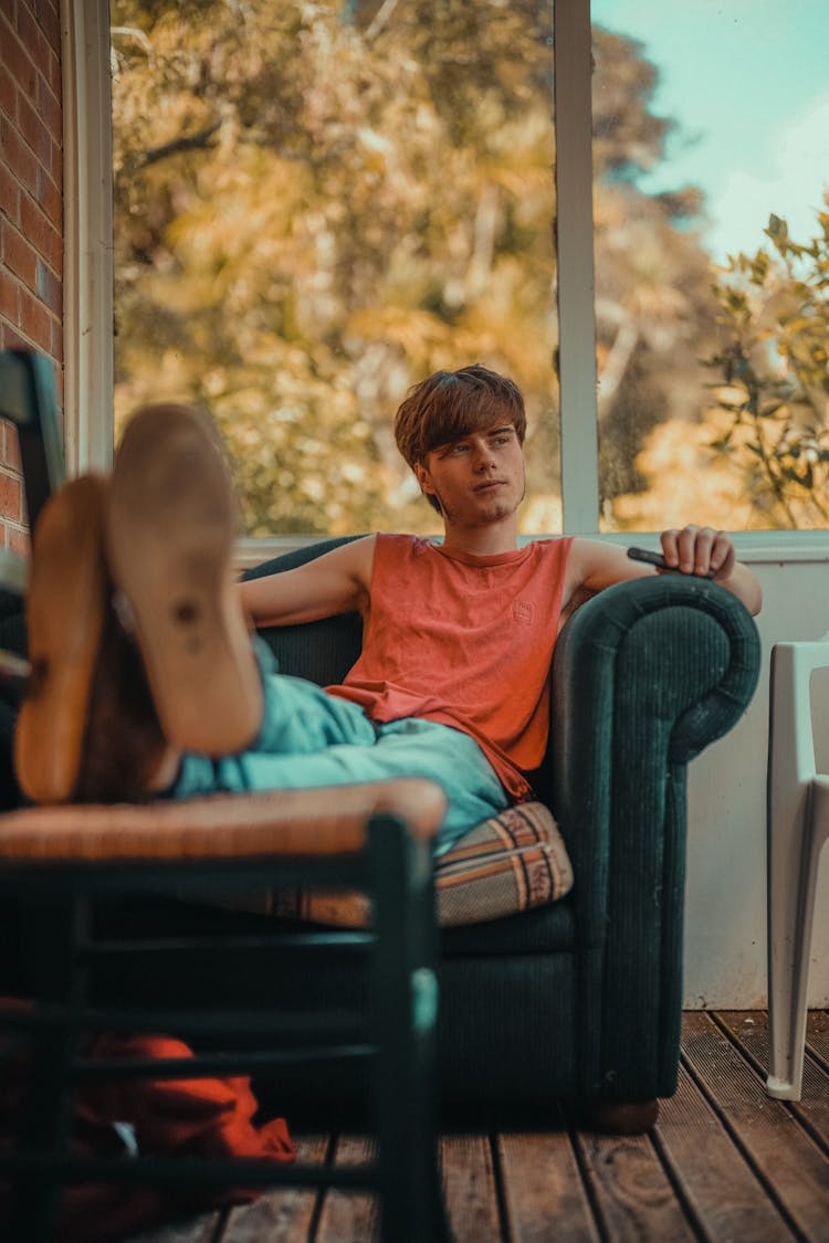 Man Sitting On Armchair With Legs On Chair