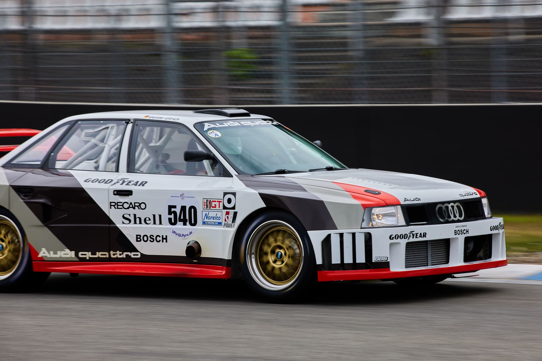 Audi Quattro race car speeding on Hockenheim circuit in motion blur.