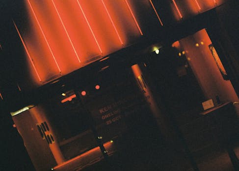 A dark, moody street scene illuminated by neon lights, capturing a mysterious urban atmosphere.