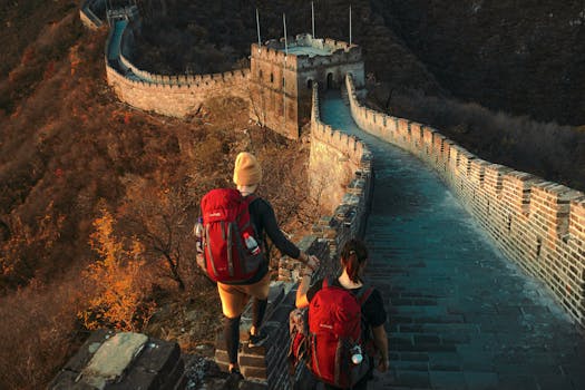 Two hikers on Great Wall, exploring ancient architecture during a sunny autumn day.