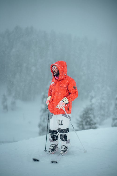 A Man in Orange Jacket Skiing on Snow Covered Mountain