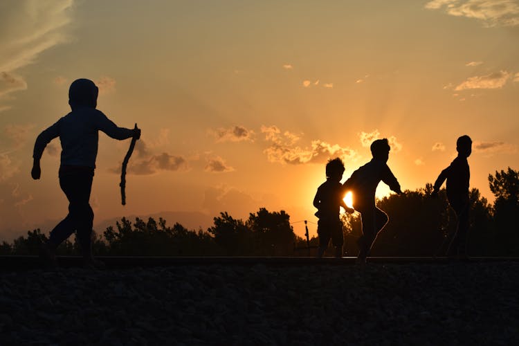 Silhouette Of Children Playing Together During Sunset