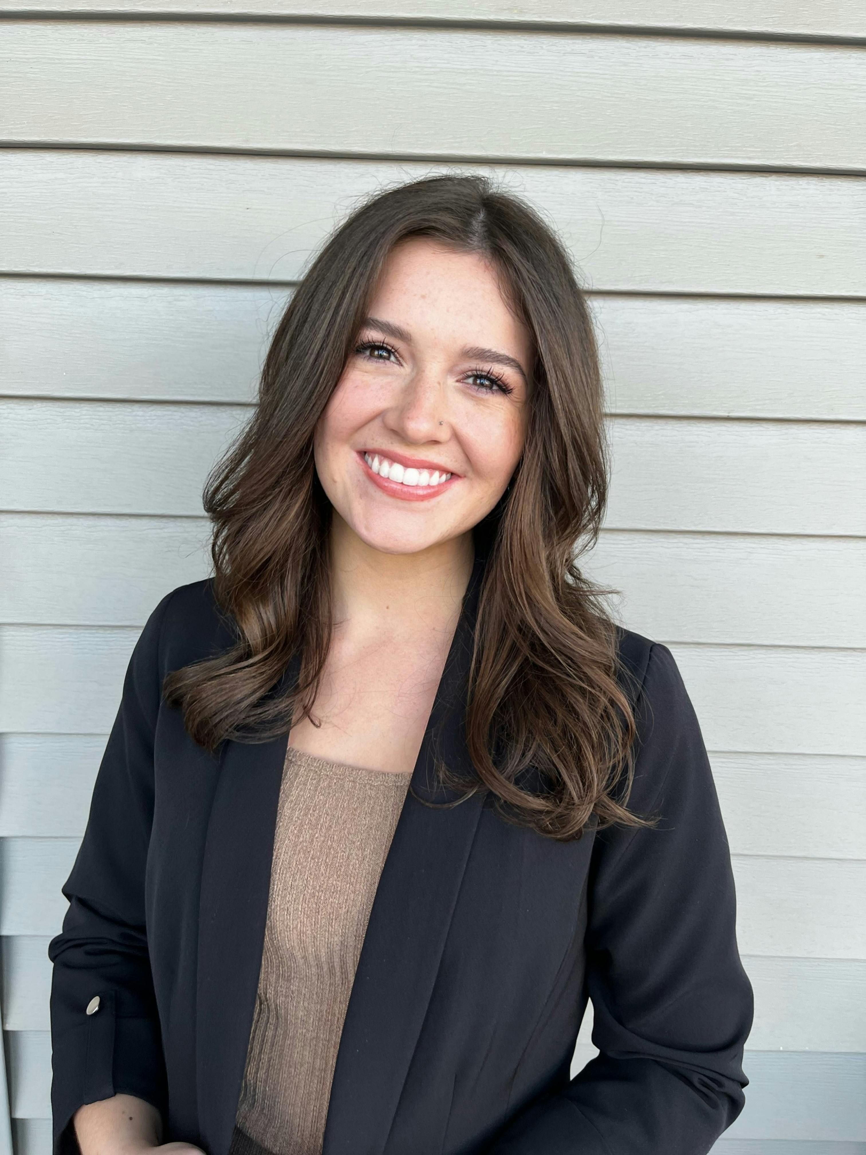 Professional portrait of a woman smiling in a black blazer, perfect for business or lifestyle uses.