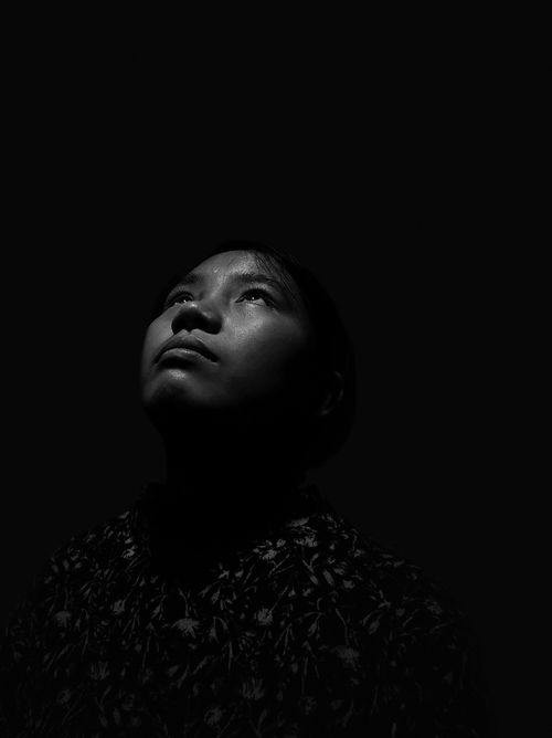Free A woman gazes upwards in a moody black and white studio shoot. Stock Photo