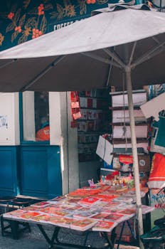 Vibrant outdoor street market stall selling various goods under a large umbrella.