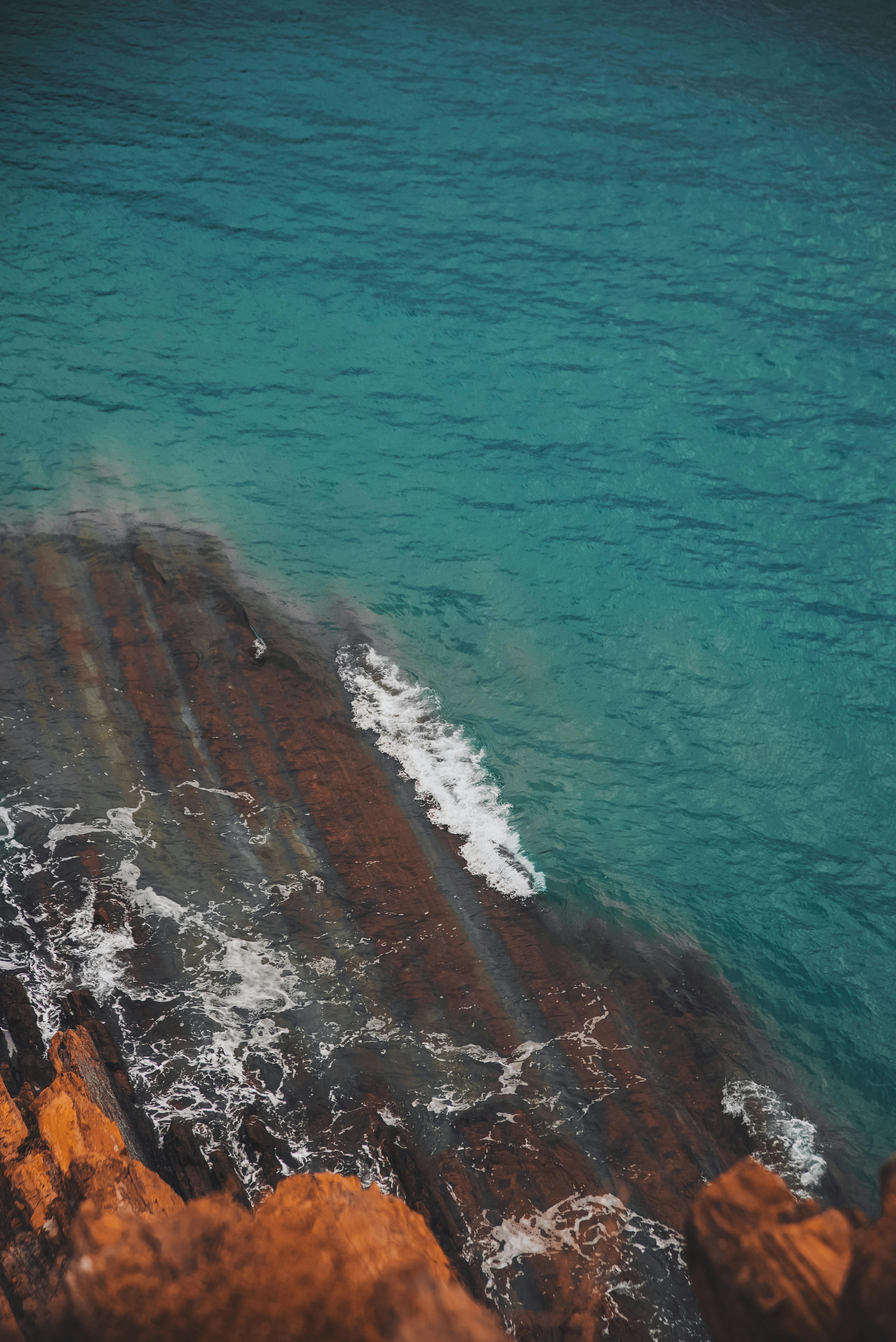 Captivating aerial shot of a rocky coastline with vibrant turquoise waters gently lapping against the shore.