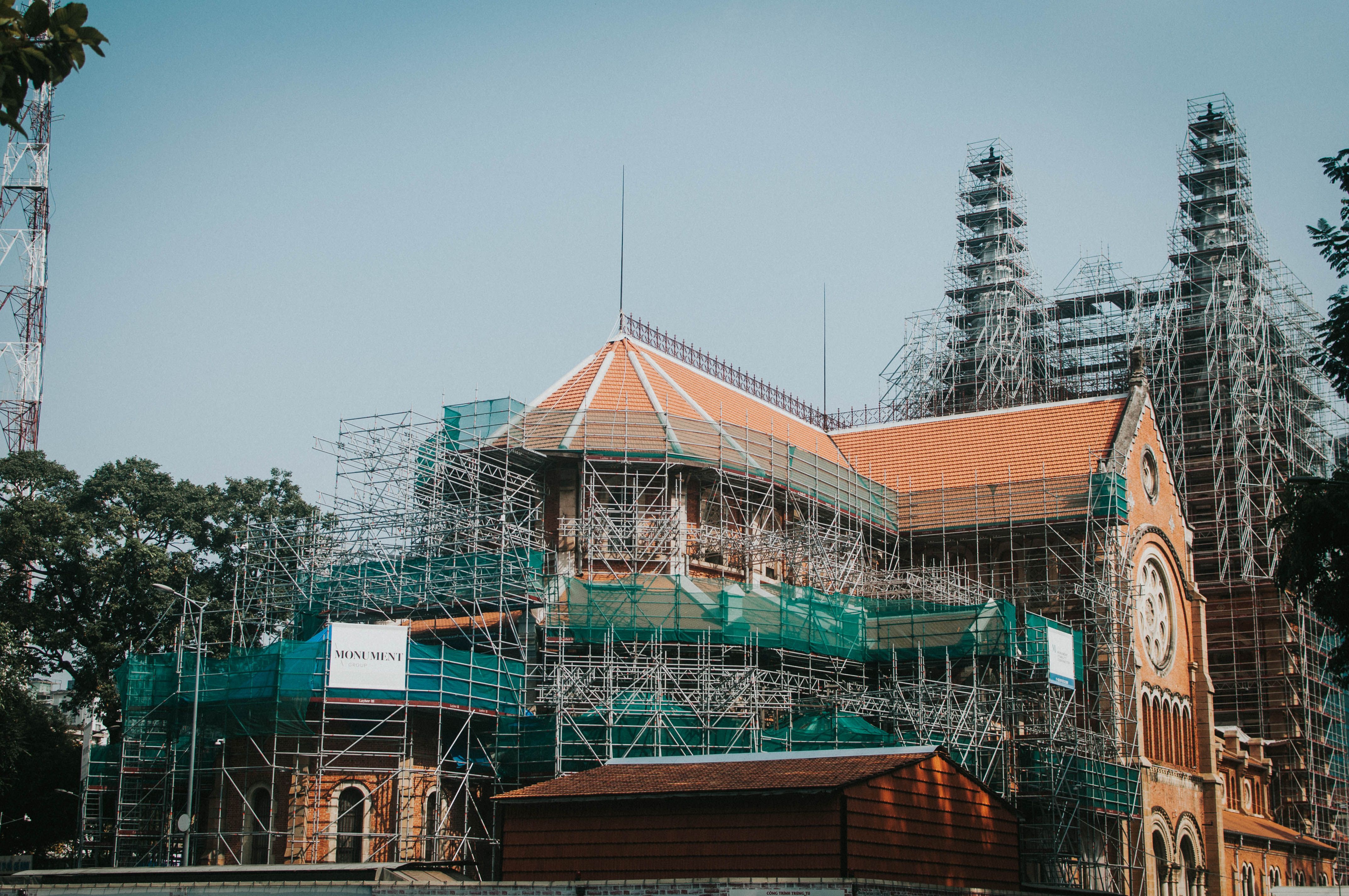A historic church building surrounded by scaffolding during renovation on a clear day.