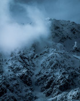 Snowy mountain peaks enveloped in dense fog, creating a mystical winter landscape.