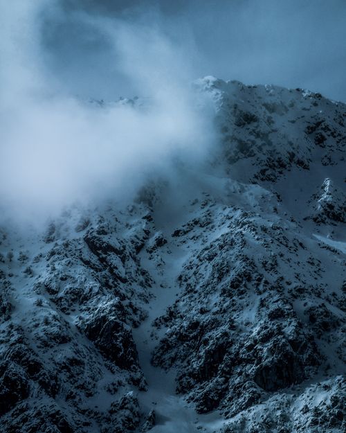 Free Snowy mountain peaks enveloped in dense fog, creating a mystical winter landscape. Stock Photo