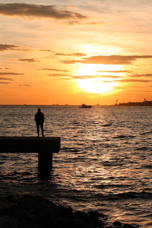 Silhouette of a Person Standing on a Dock at Sunset 