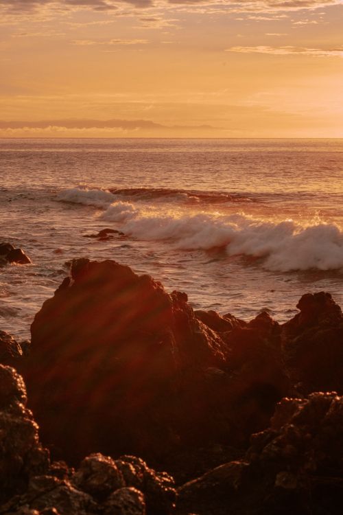 Free Sunset over a rocky coastline with waves crashing dramatically. Vibrant and serene. Stock Photo