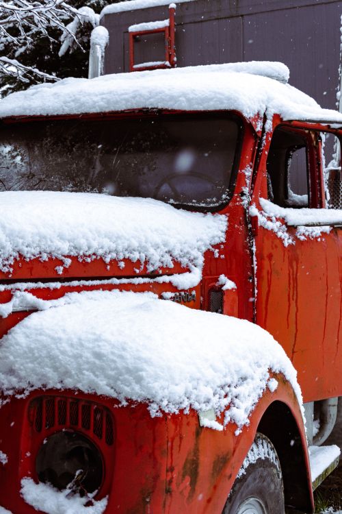 Free A vintage red truck parked outdoors, blanketed by fresh winter snowfall, creates a picturesque winter scene. Stock Photo