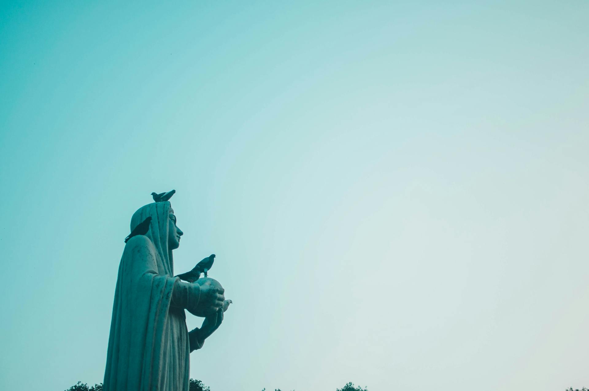 A statue with birds perched against a clear blue sky, offering a serene scene.